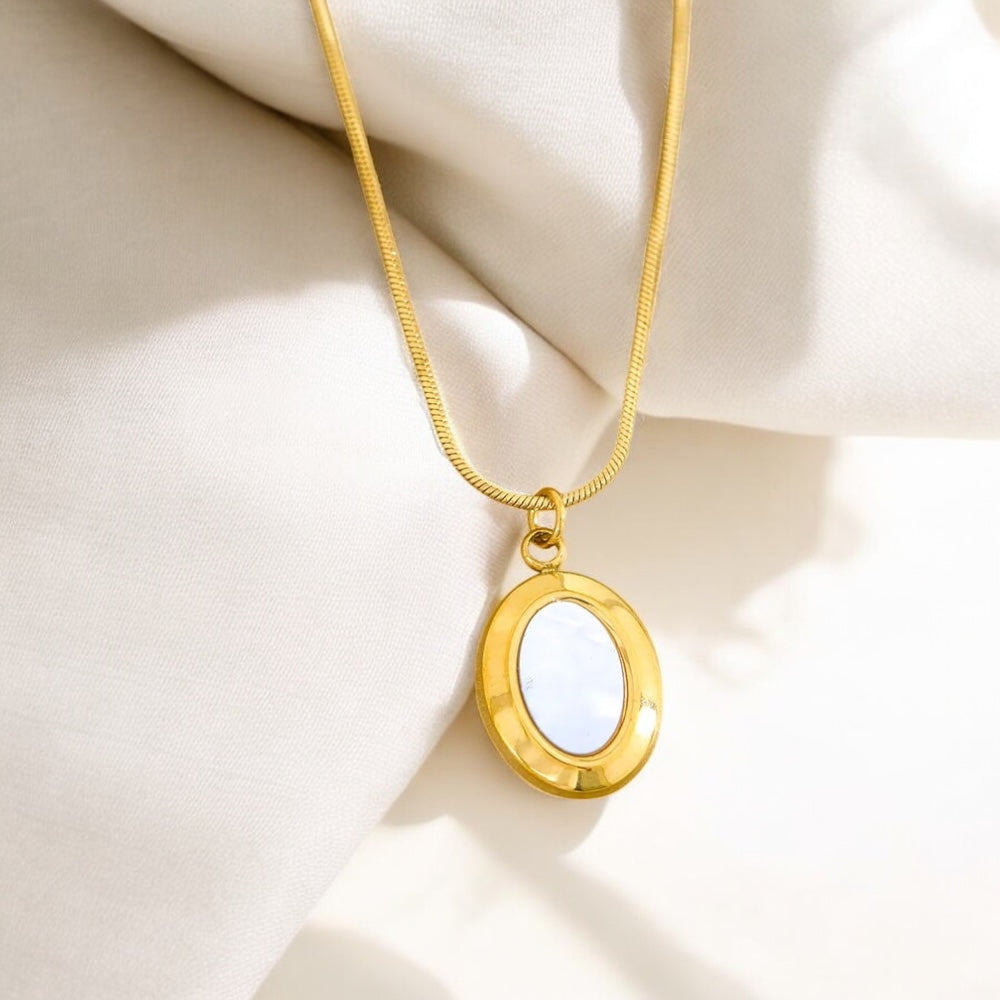 Gold necklace with a round pendant on a beige fabric background