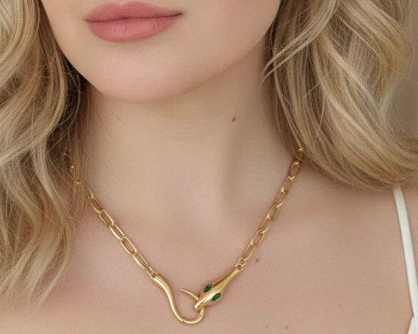 Close-up of a woman wearing a gold necklace with a green pendant.