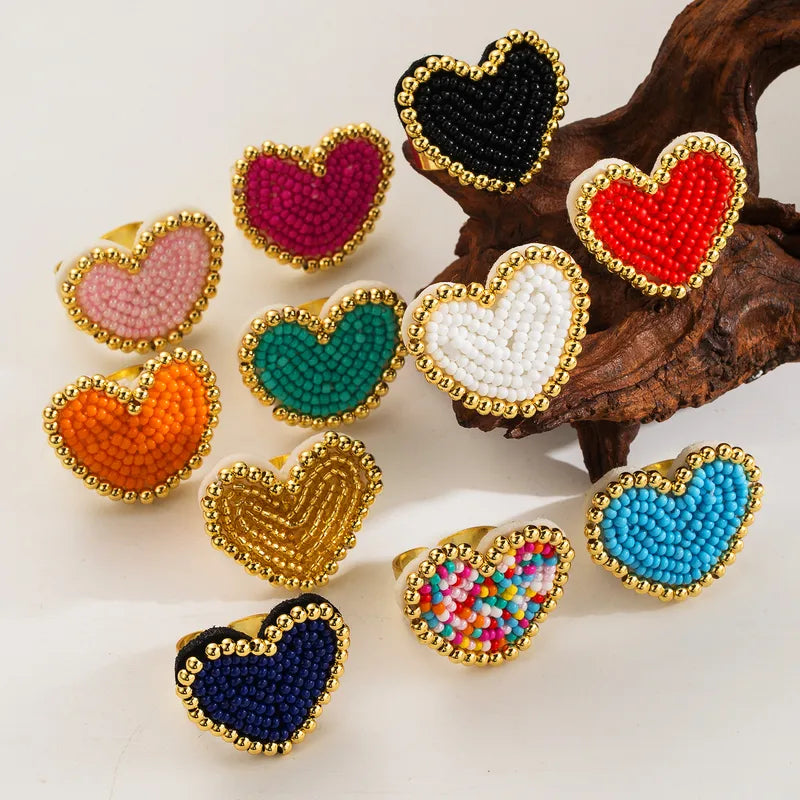 Colorful heart-shaped beaded rings on a wooden surface