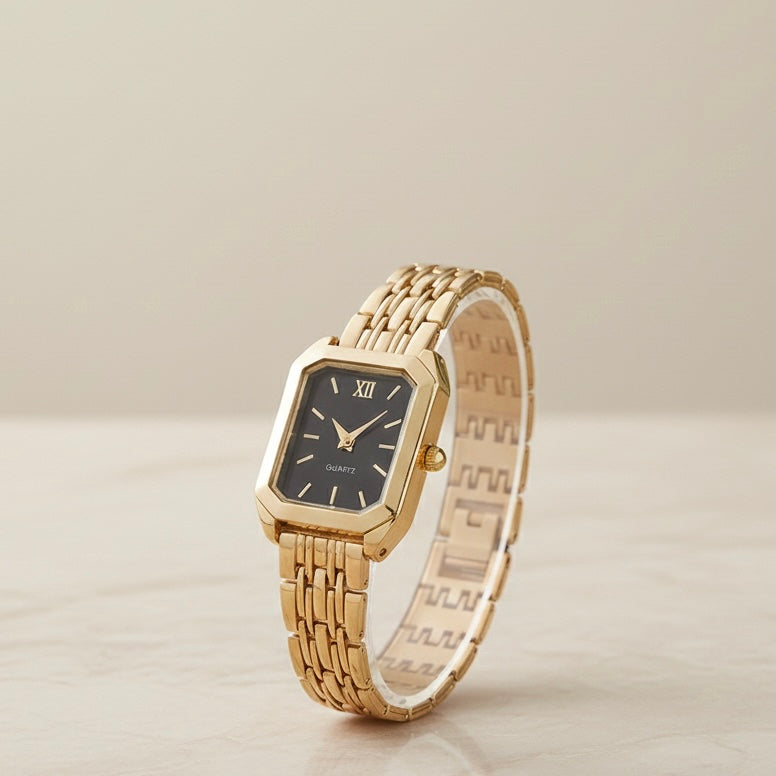 Gold watch with a black face on a light beige background