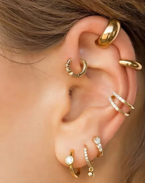 Close-up of an ear wearing multiple gold hoop earrings