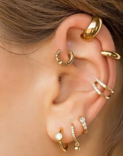 Close-up of an ear wearing multiple gold hoop earrings