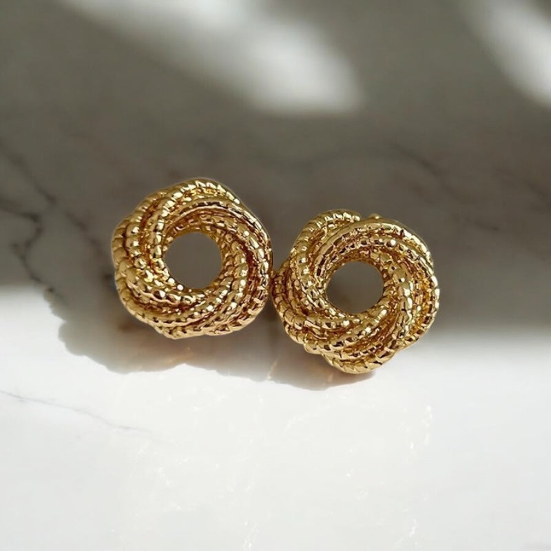 Gold circular earrings on a light background