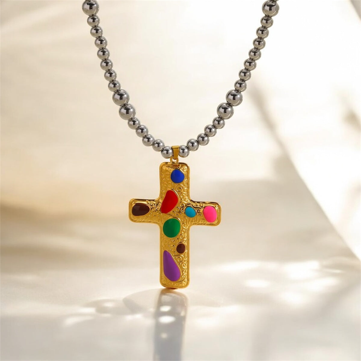Necklace with a colorful cross pendant on a light background