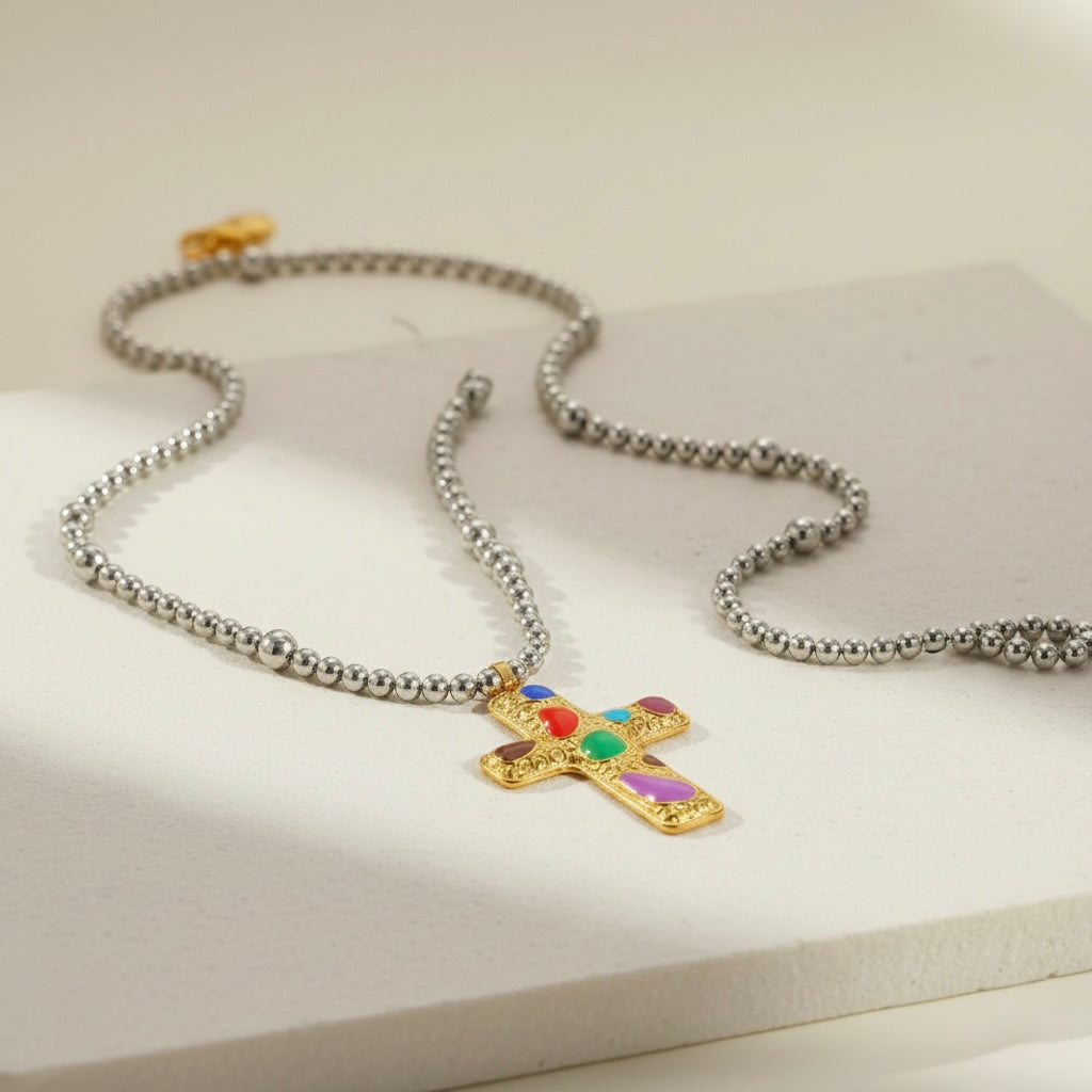 Necklace with a gold cross pendant featuring colorful stones on a light background