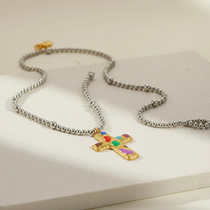 Necklace with a gold cross pendant featuring colorful stones on a light background