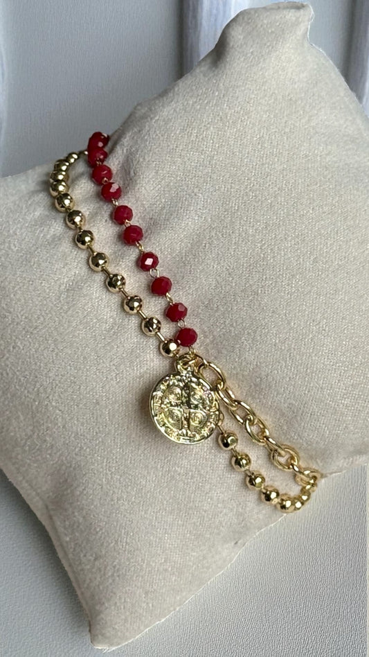 Necklace with red beads and gold chain on a white cushion