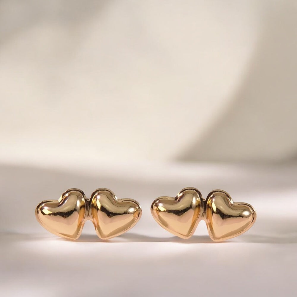 Pair of gold heart-shaped earrings on a light background