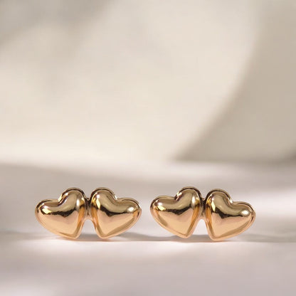 Pair of gold heart-shaped earrings on a light background