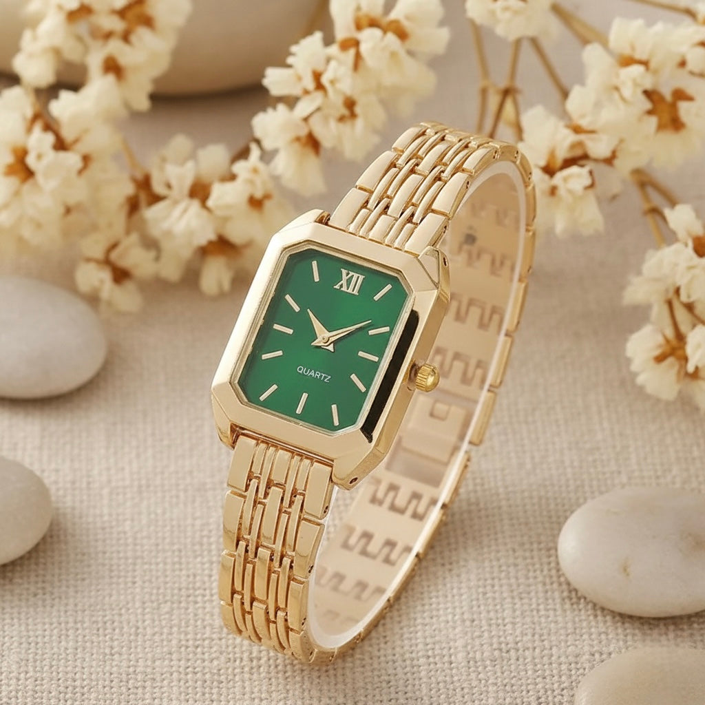 Gold watch with a green face on a textured surface with flowers and stones