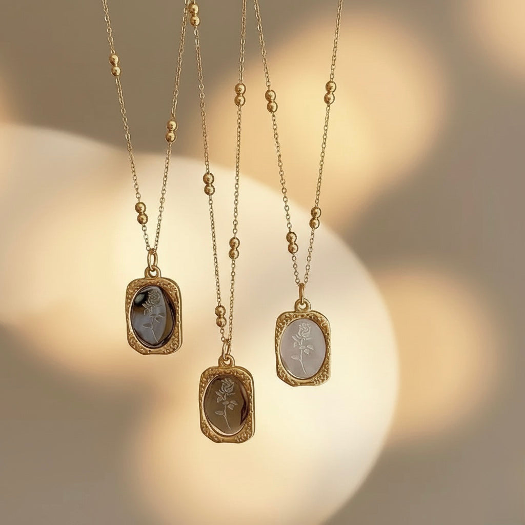 Three gold necklaces with engraved pendants on a soft focus background