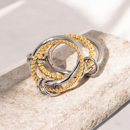 Three gold and silver rings stacked on a textured surface