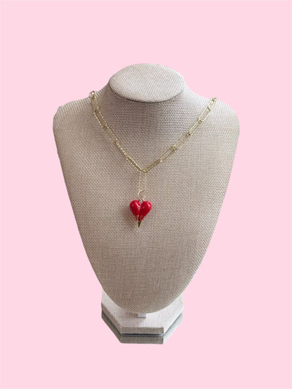 Necklace with a red heart pendant on a mannequin bust against a pink background