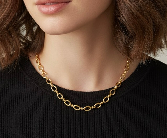 Gold chain necklace worn by a person with a blurred background