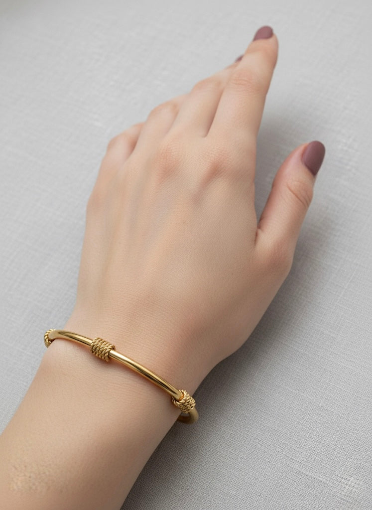 Gold bracelet on a hand against a neutral background