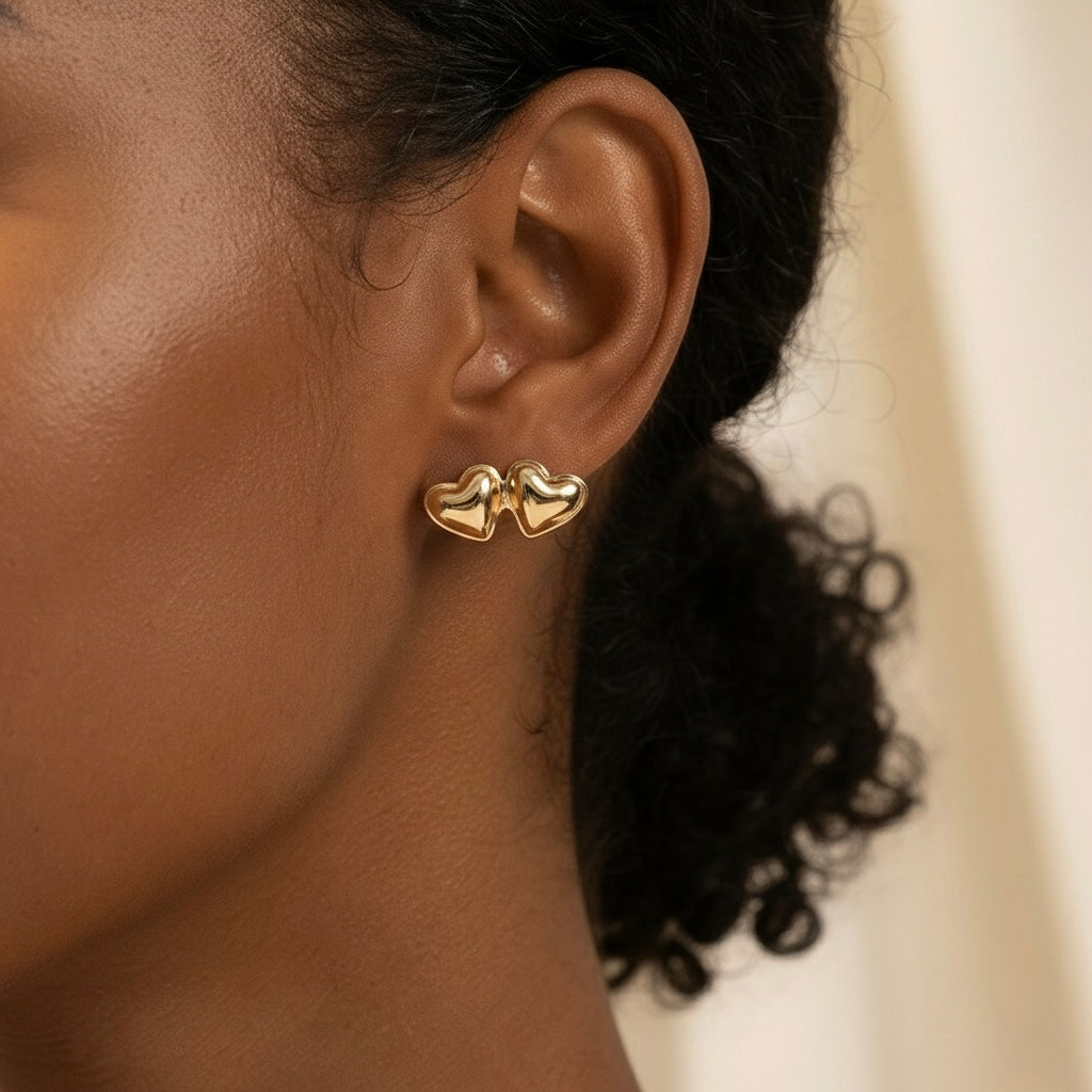 Close-up of an ear wearing a gold heart-shaped earring with a blurred background
