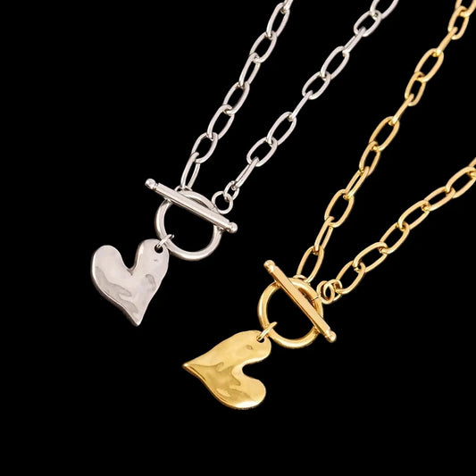 Two heart-shaped pendants on chains against a dark background