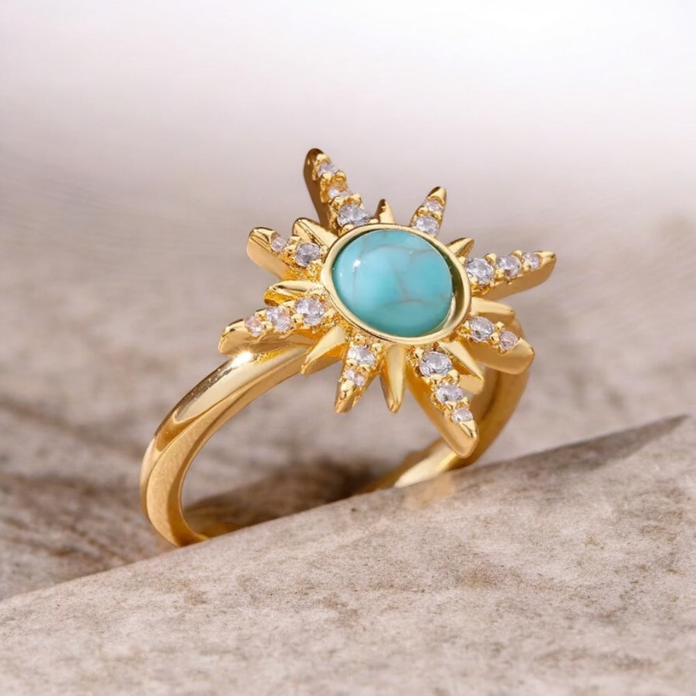 Gold ring with turquoise stone on a stone surface