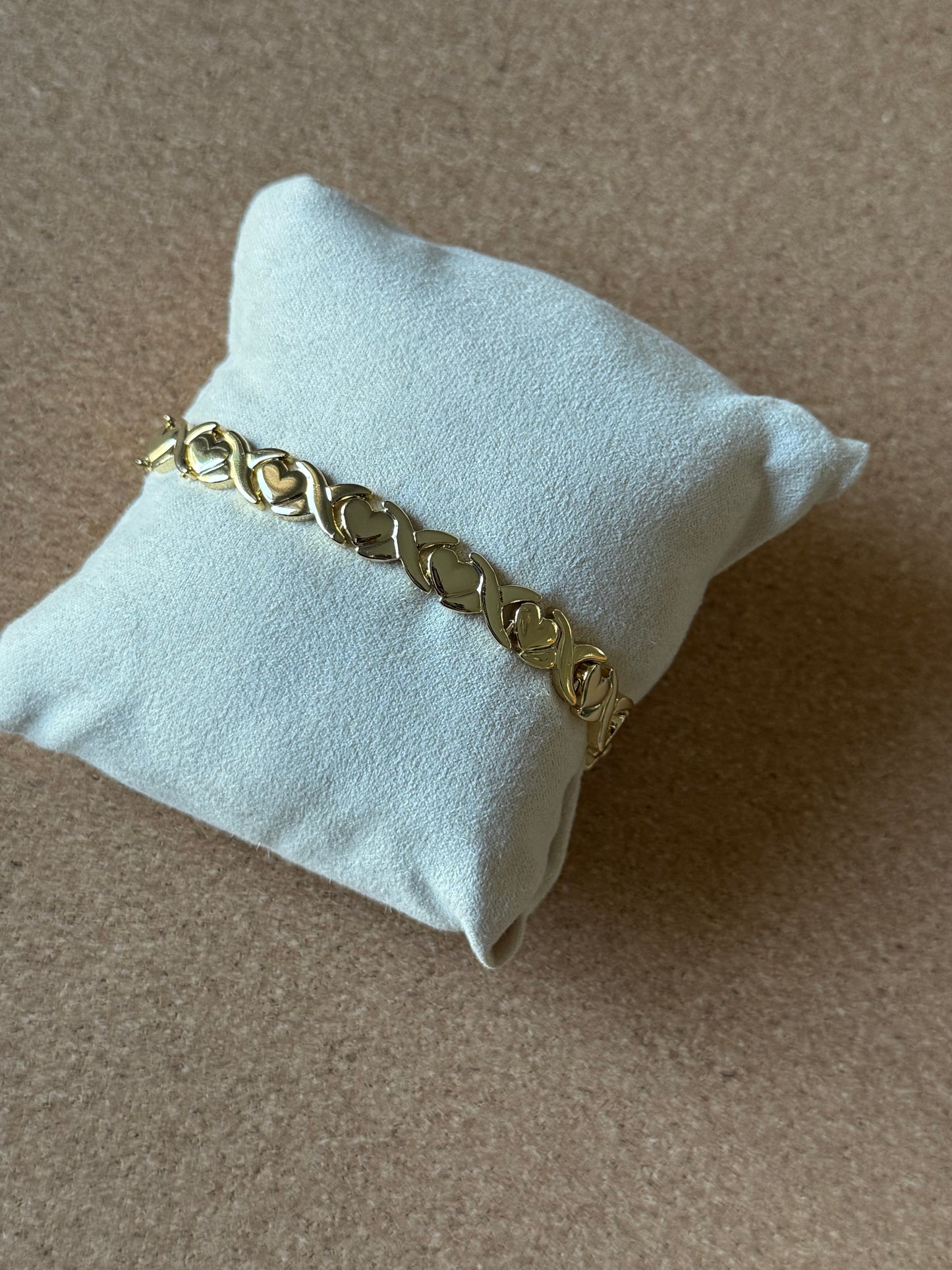 Gold chain bracelet on a light blue cushion with a brown background