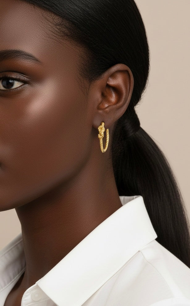 Close-up of a woman wearing gold hoop earrings with a neutral background