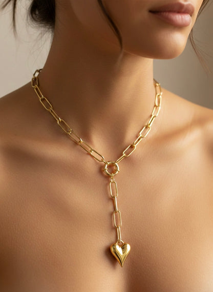 Gold chain necklace with a heart pendant on a neutral background