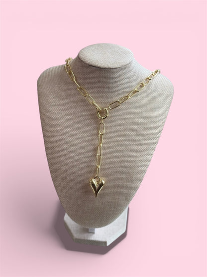 Gold necklace with a pendant on a gray mannequin bust against a pink background