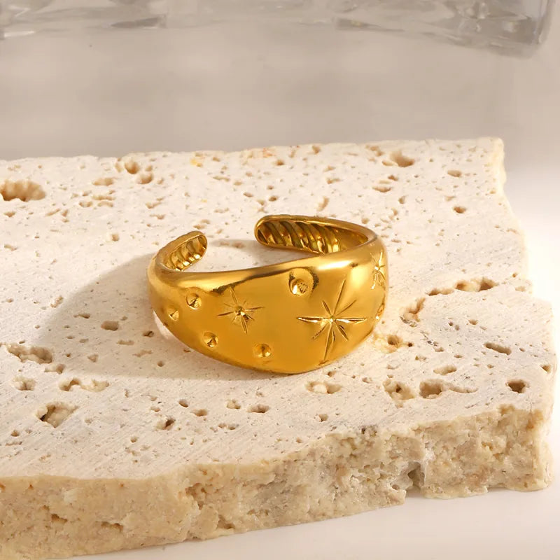 Gold ring with star and moon designs on a textured stone surface