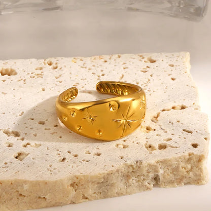 Gold ring with star and moon designs on a textured stone surface