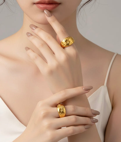 Close-up of a woman's hand wearing two gold rings on a neutral background