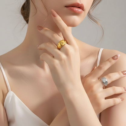 Close-up of a woman's hand wearing two rings, one gold and one silver, on a neutral background.