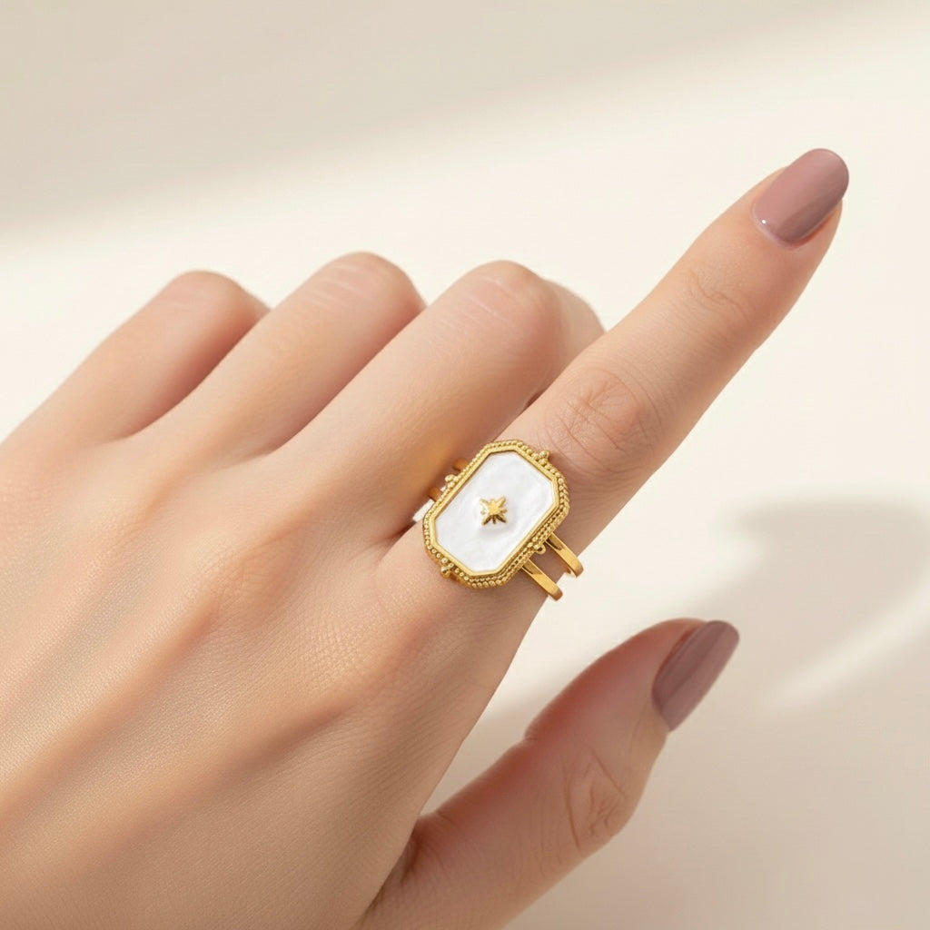 Gold ring with a white face on a hand against a neutral background