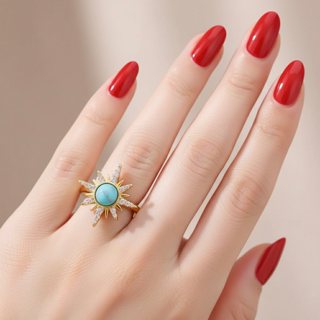 Hand wearing a gold ring with a turquoise stone against a neutral background