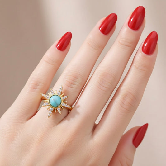Hand wearing a gold ring with a turquoise stone against a neutral background