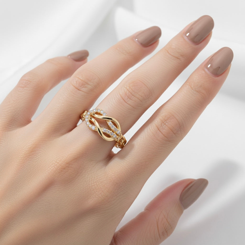 Gold ring on a hand with beige nail polish against a light background