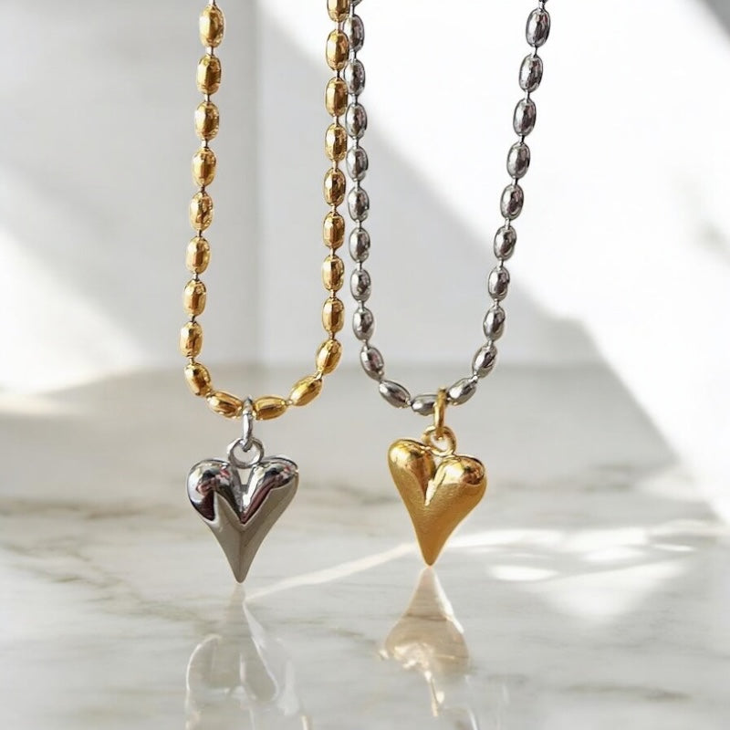 Two heart-shaped pendants on necklaces with a marble background