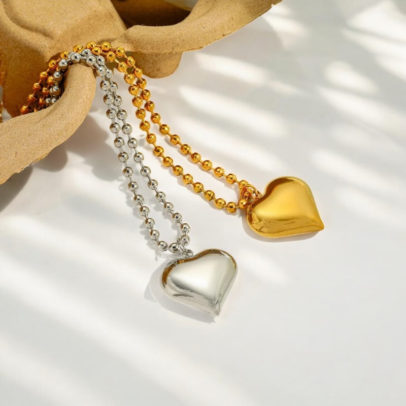 Two heart-shaped pendants, one gold and one silver,