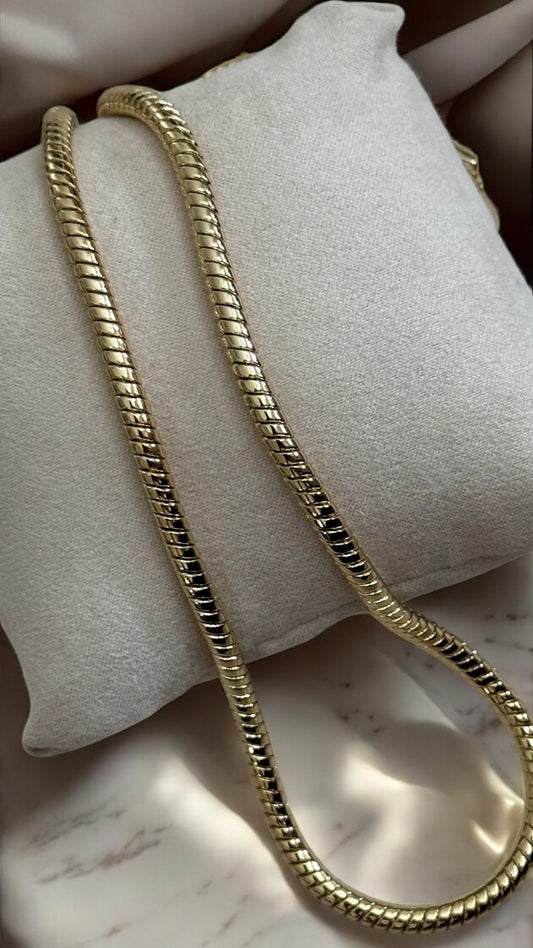 Gold chain on a white cushion with a marble surface