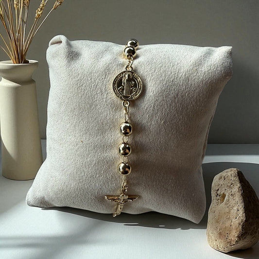 Gold rosary on a white pillow with a neutral background