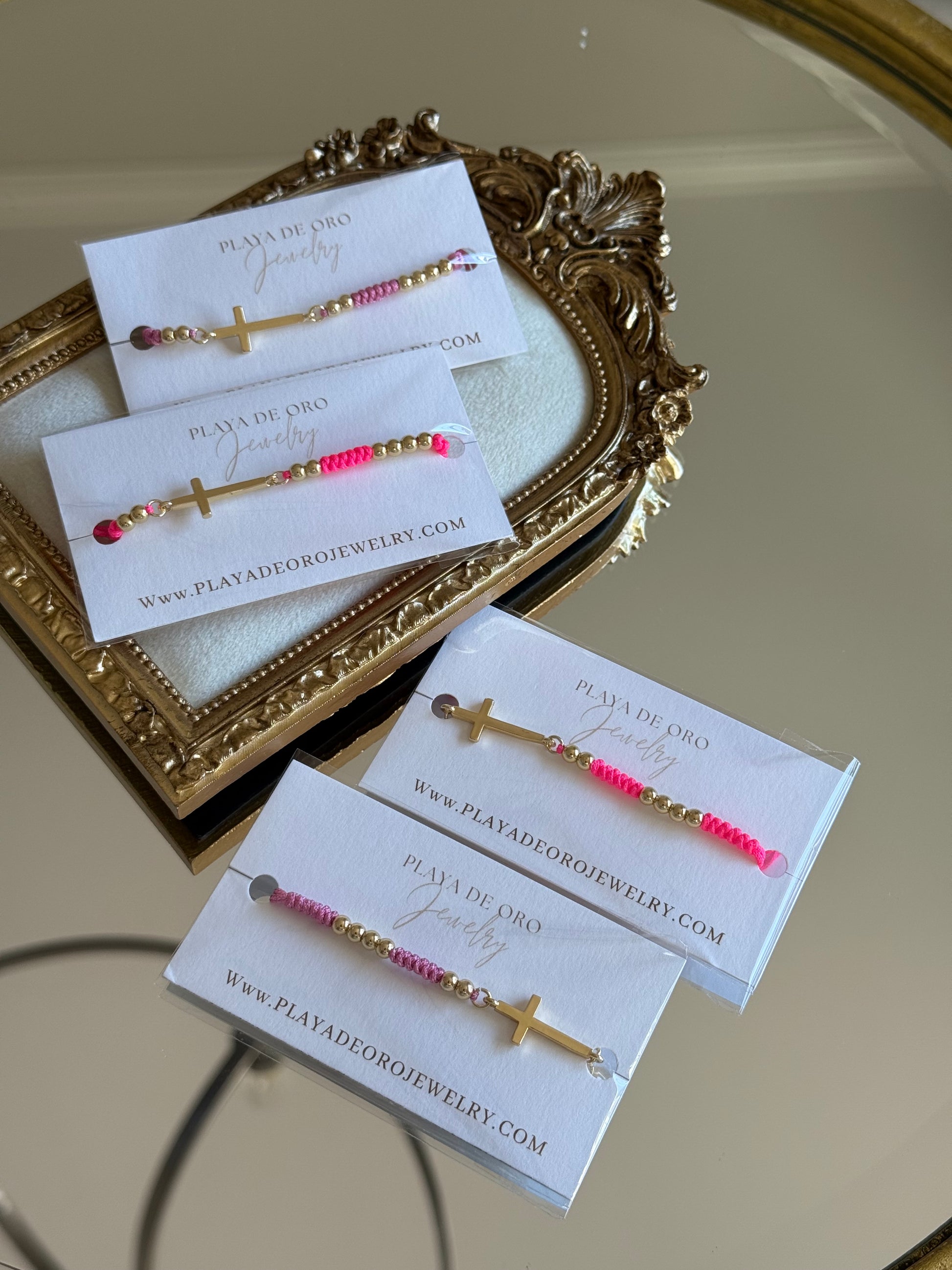 Jewelry set with pink and gold elements on cards, displayed against a decorative mirror.