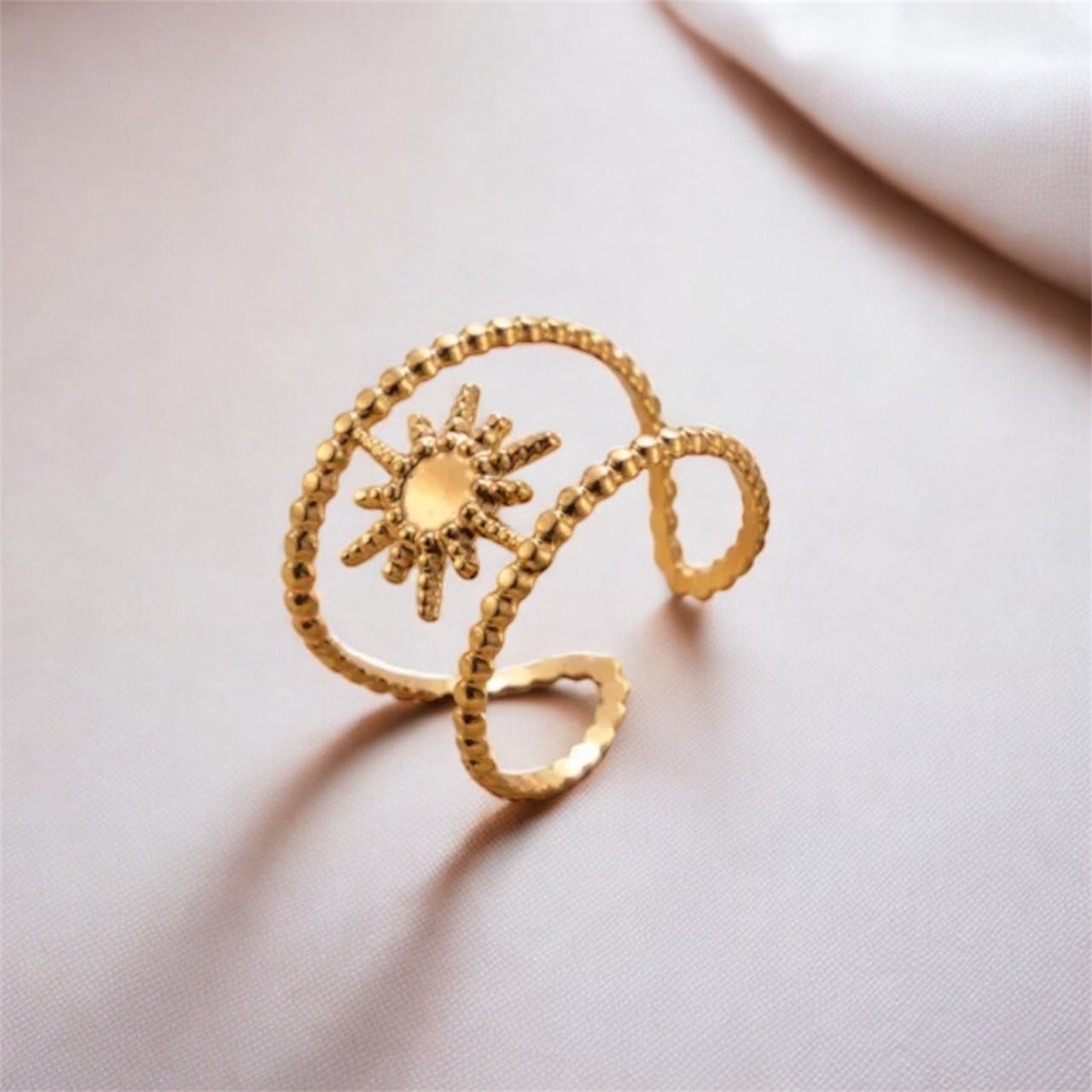 Gold ring with sun design on a light gray background