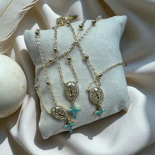 Gold and silver necklaces with turquoise pendants on a white cushion
