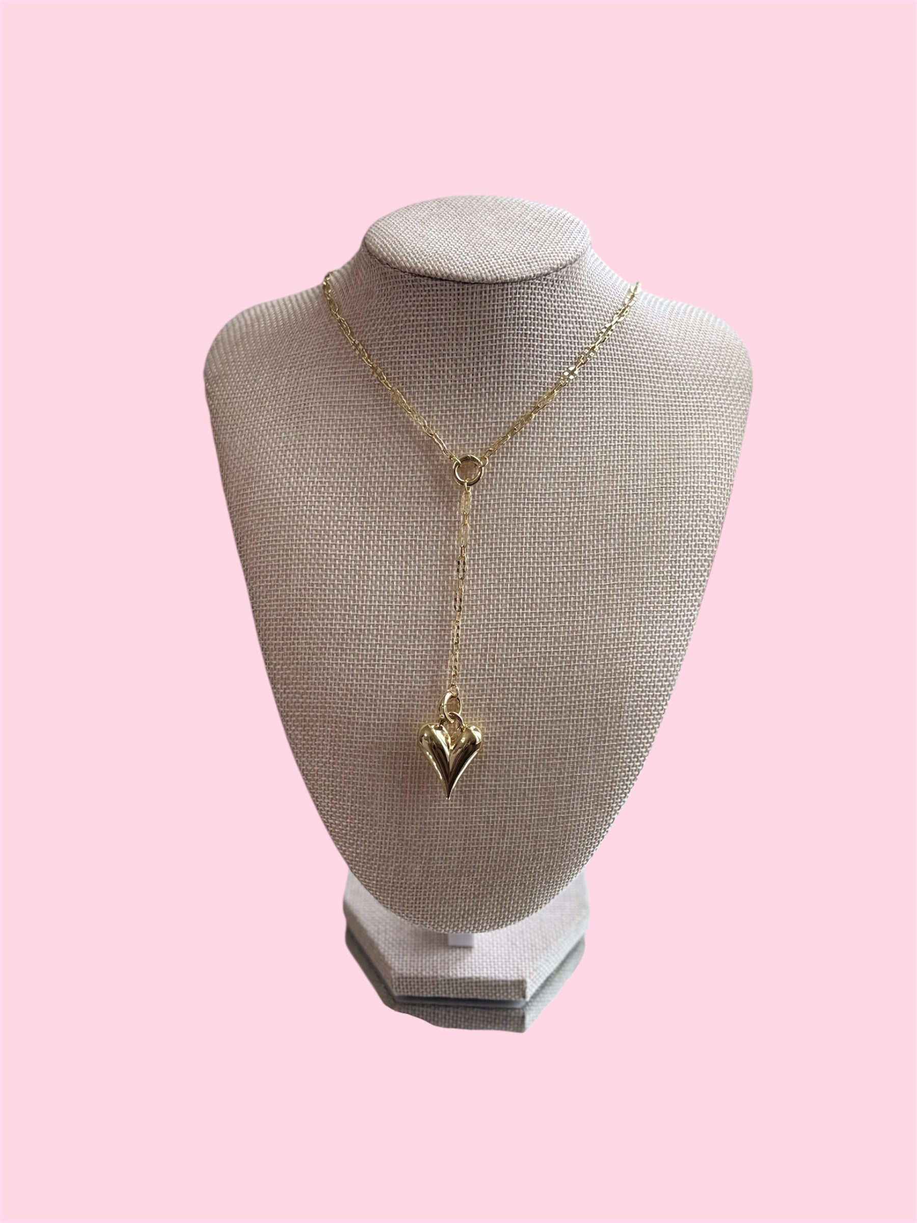 Gold necklace on a mannequin bust against a pink background