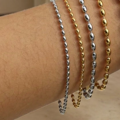 beaded Bracelet, one silver and one gold, draped over a person's arm.
