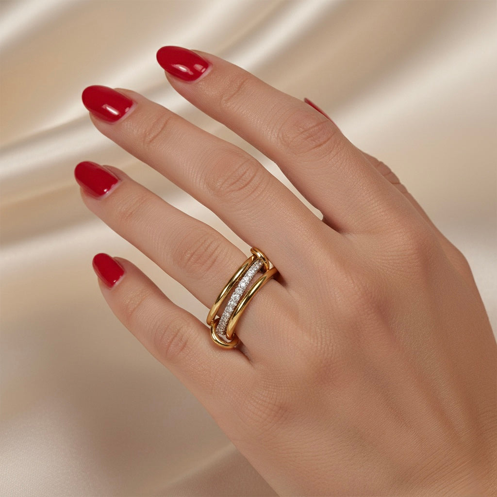 Hand wearing a gold ring with red nail polish on a beige background