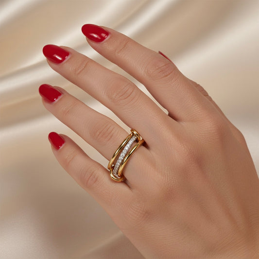 Hand wearing a gold ring with red nail polish on a beige background