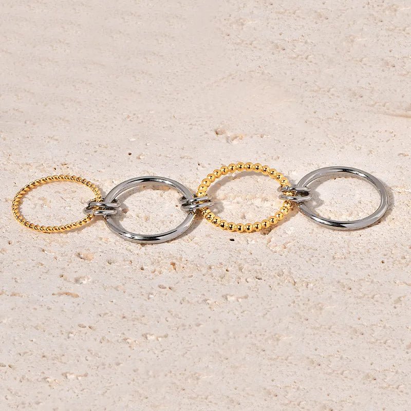 Two gold and silver rings on a textured beige surface