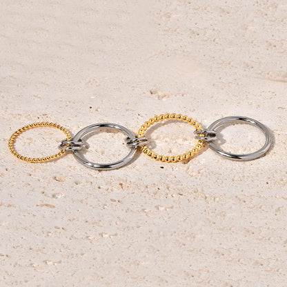 Two gold and silver rings on a textured beige surface