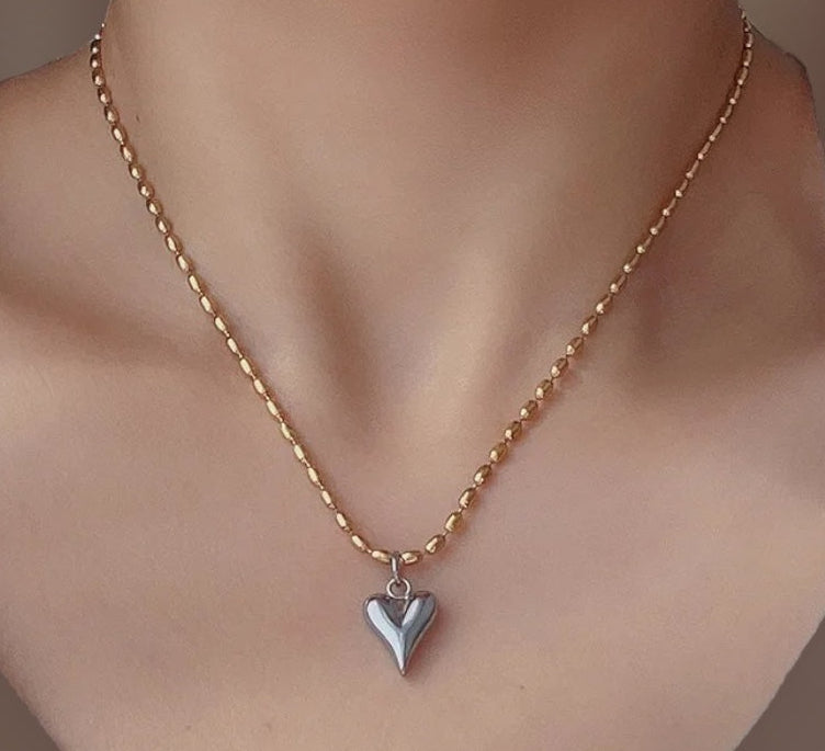 Gold necklace with a heart-shaped pendant on a mannequin bust.