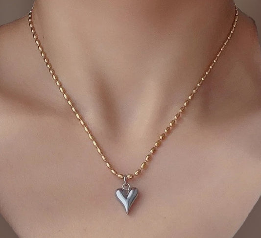 Gold necklace with a heart-shaped pendant on a mannequin bust.