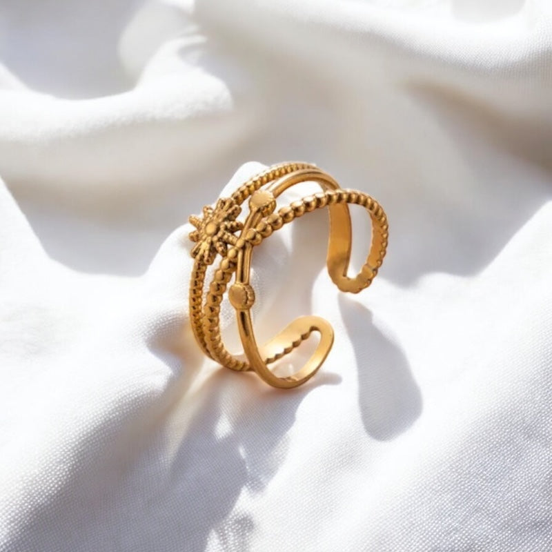 Gold ring with intricate design on a white fabric background